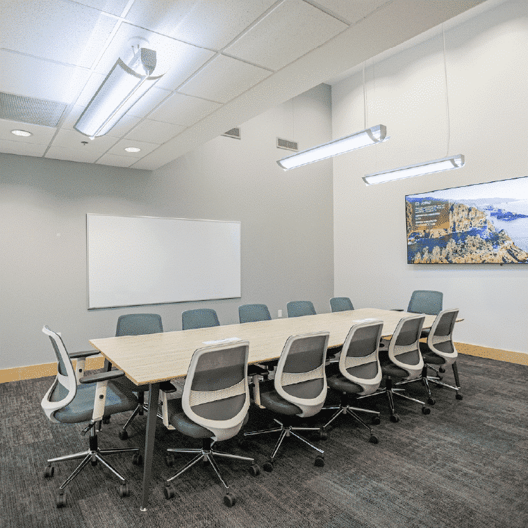 Conference room for rent at Shift set up with a conference table, chairs, and a connected TV.